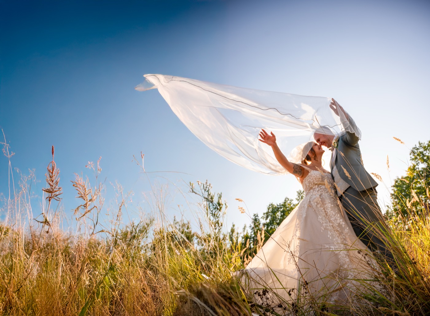 Brautpaar im goldenen Feld, Schleier im Wind — Hochzeitsfotografie Berlin und Umgebung